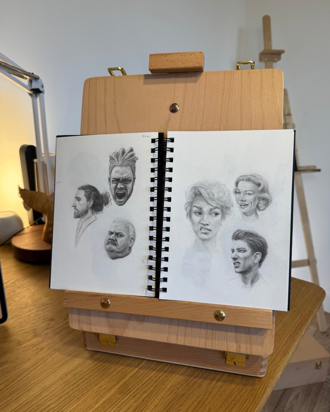 Six croquis de portraits en noir et blanc dans un carnet de croquis, montrant des esquisses de visages expressifs